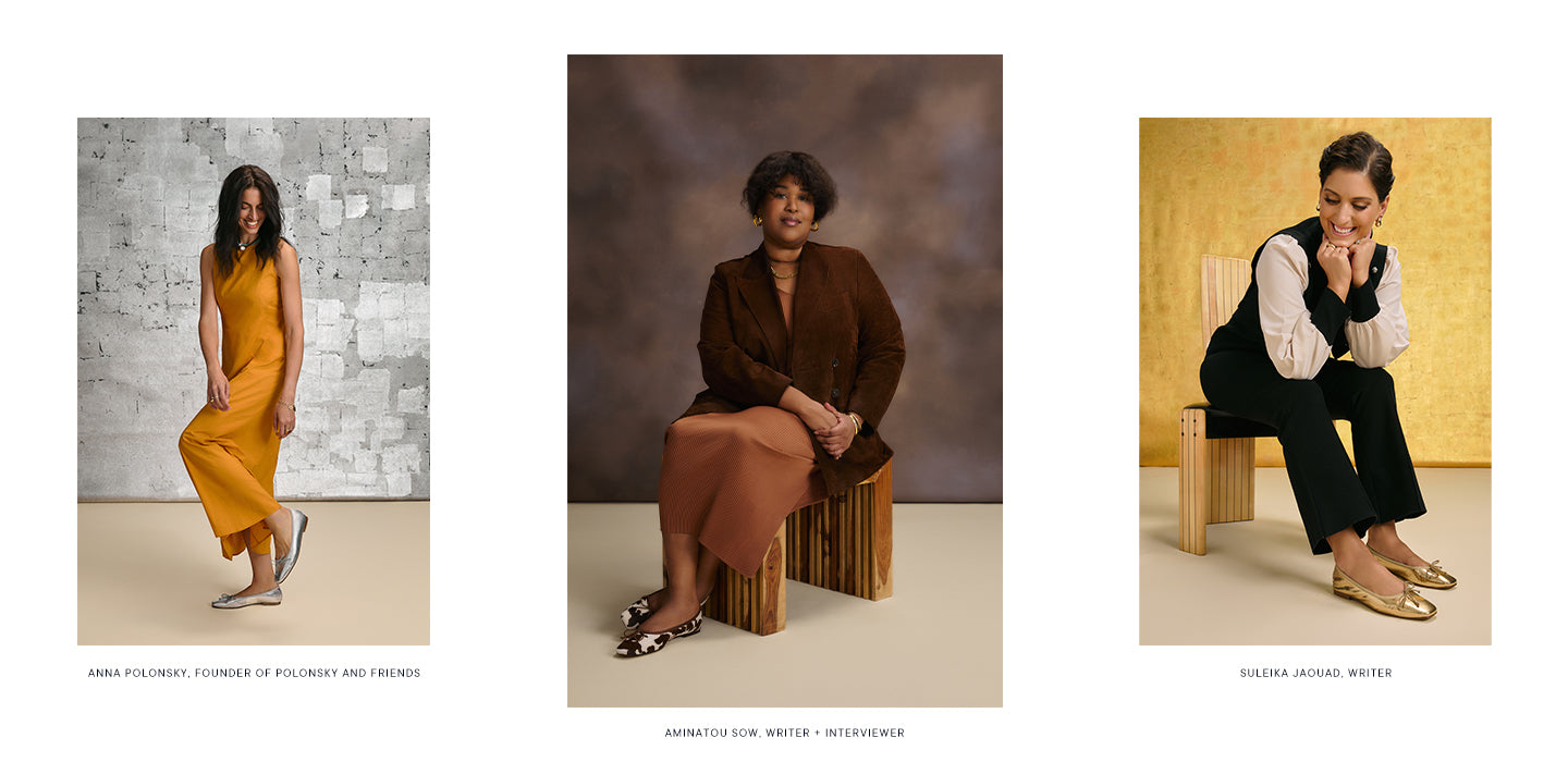 Three women sit on wooden stools against simple backgrounds. From left to right: a woman in a mustard dress, a woman in a brown blazer and rust dress, and a woman in black trousers with a white blouse layered under a black vest.
