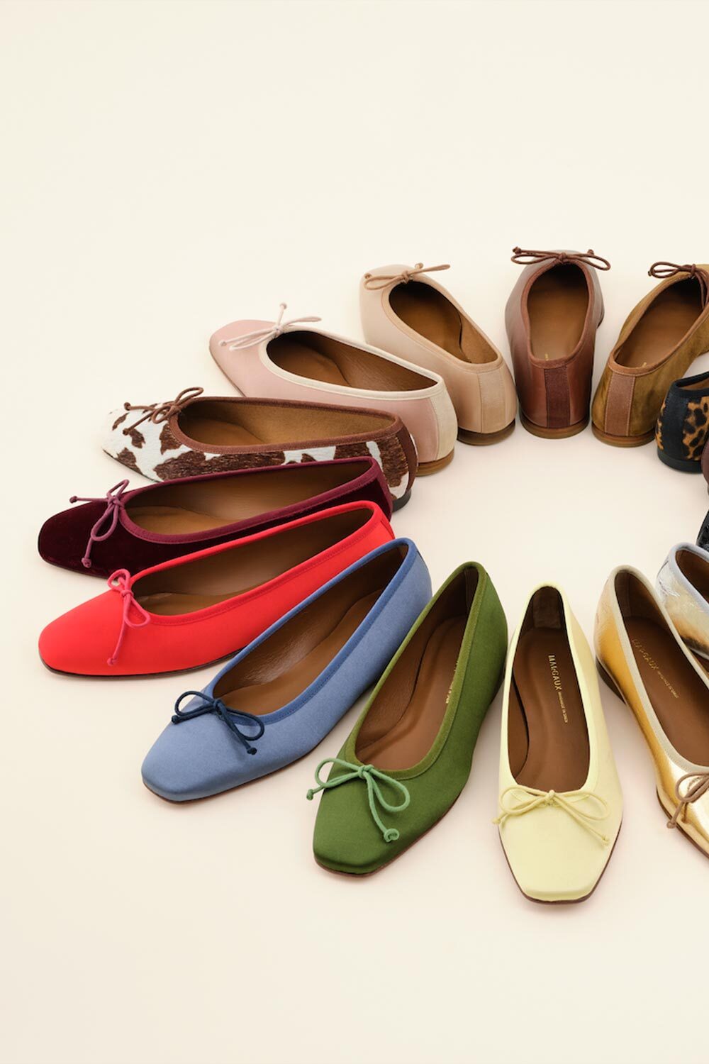 A semicircle of womens ballet flats in various colors and patterns, including red, blue, green, yellow, pink, brown, and animal print, arranged neatly on a light background.