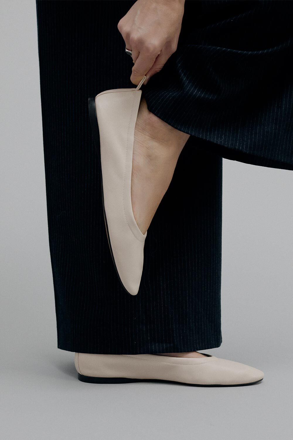 Person wearing beige flat shoes with a plain background