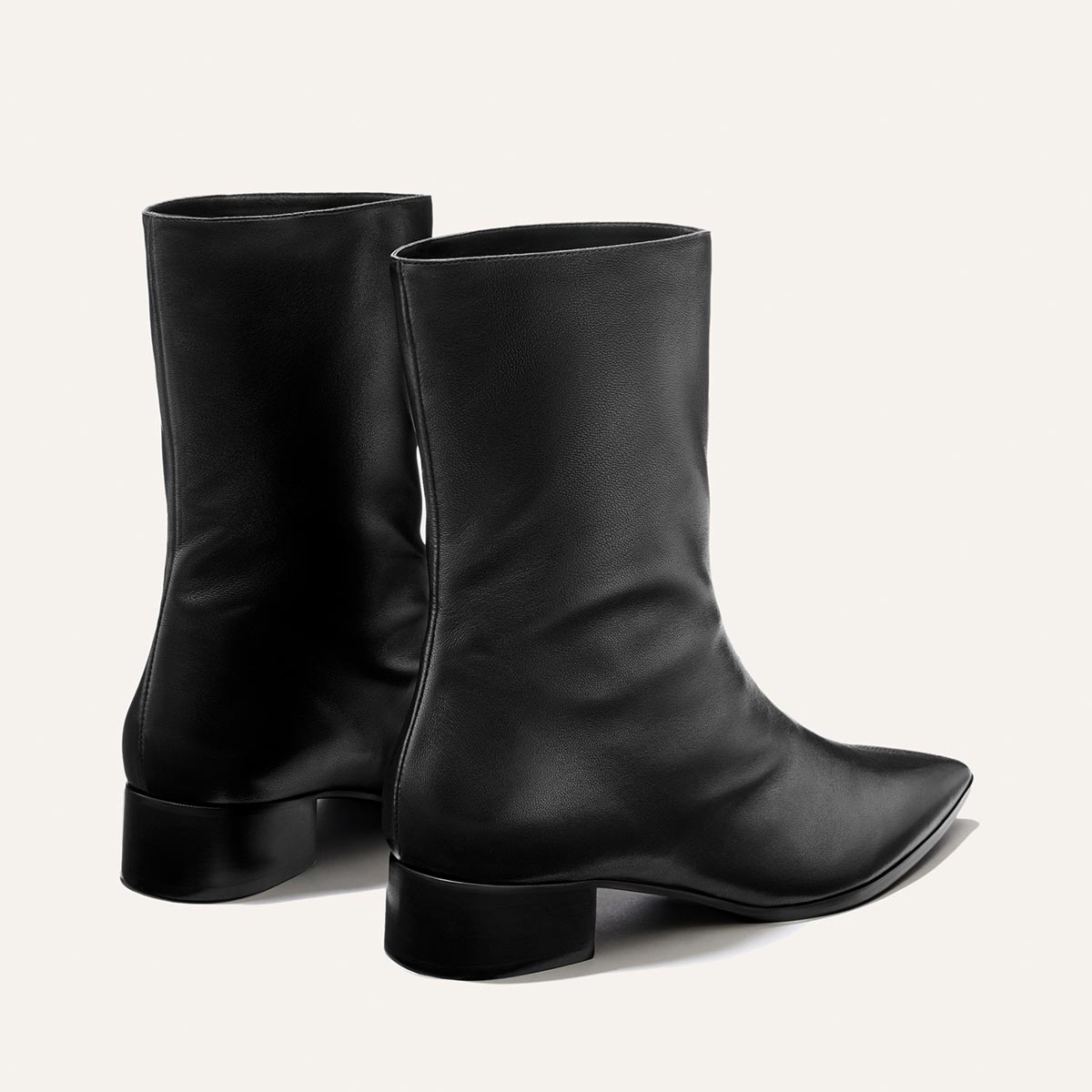 A pair of The Hayes Boot - Black Nappa by Margaux, featuring black leather, mid-calf height, square heels, and pointed toes, displayed on a plain light background.