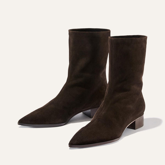 A pair of The Hayes Boot in Dark Chocolate Suede by Margaux, featuring pointed toes and low block heels, brings subtle bohemian flair, displayed on a plain light background.
