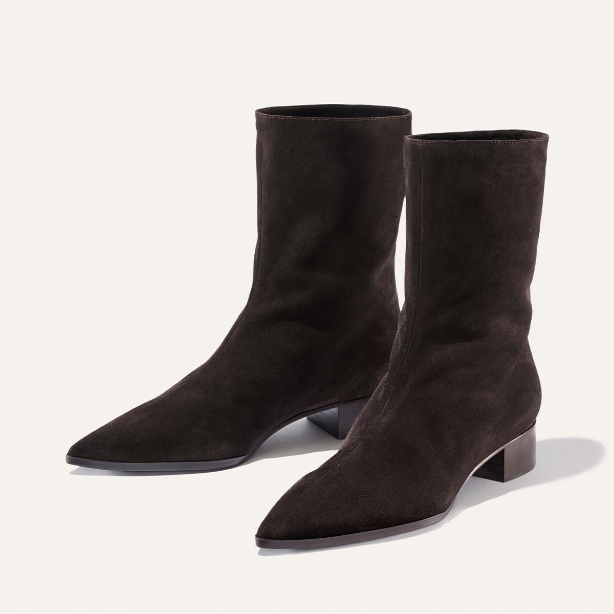 A pair of The Hayes Boot in dark chocolate suede by Margaux, featuring pointed toes and low block heels, displayed on a light background.