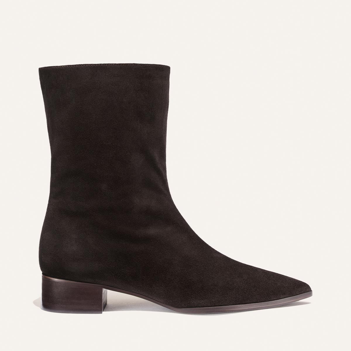 The Hayes Boot by Margaux—a single, dark chocolate suede ankle boot—features a low block heel and a pointed toe, showcased against a plain light background.