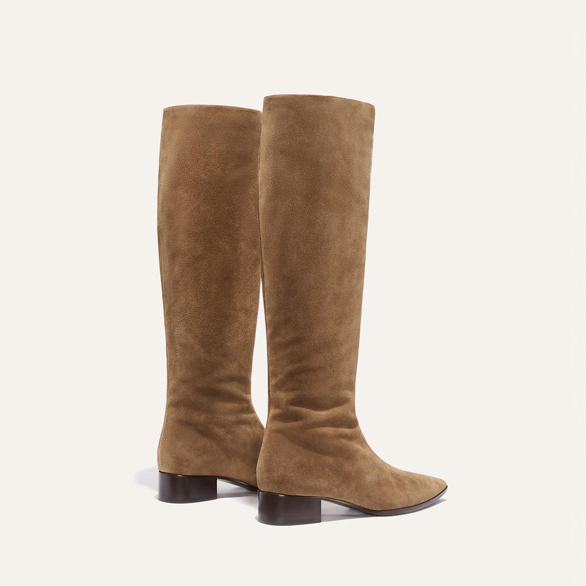 The Hayes Knee-High Boot - Driftwood Suede by Margaux features soft tan suede and low, dark brown block heels. Expertly crafted from high-quality leather for both style and comfort, these knee-high boots are presented upright against a plain light background.