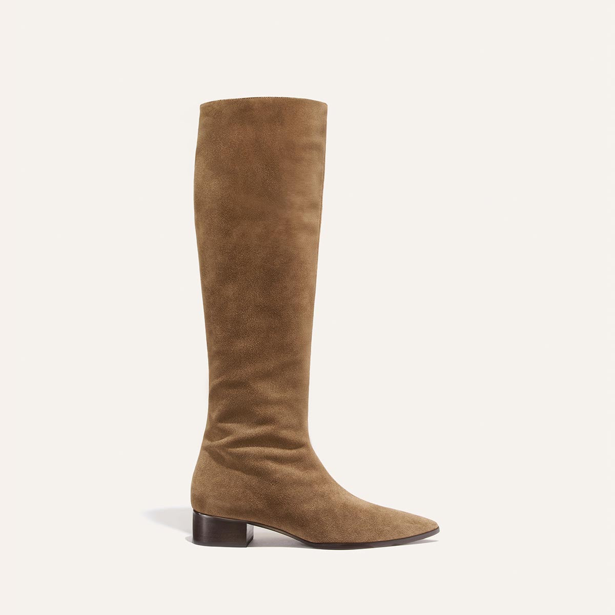 The Hayes Knee-High Boot – Driftwood Suede by Margaux is a single handmade tan suede tall boot with a low, chunky heel and an almond-shaped toe, designed with a flexible sole for extra comfort, shown against a plain off-white background.