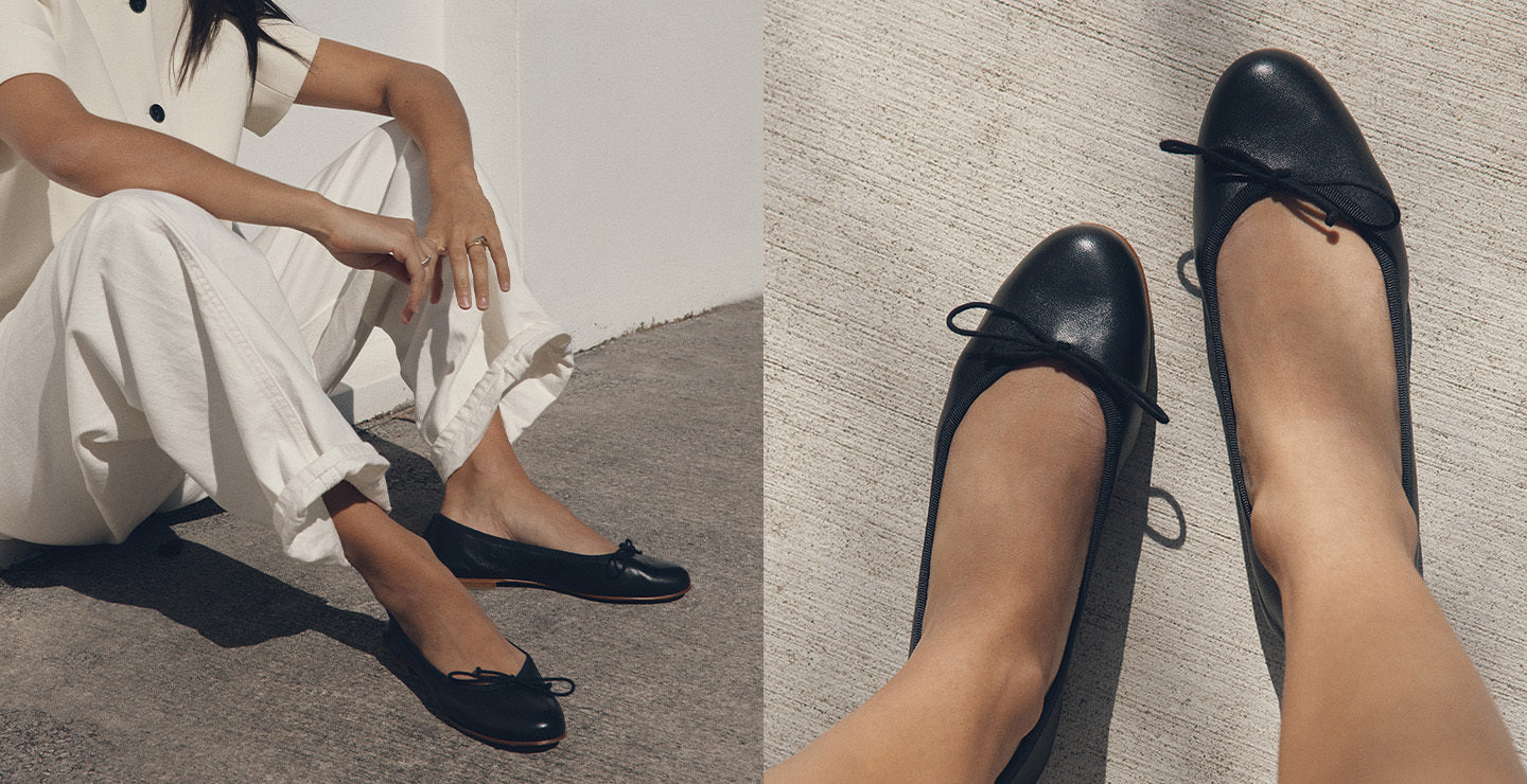 Black flats worn by a person sitting on the floor with a neutral background
