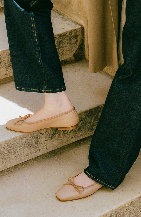 Person wearing beige flats with a bow detail on steps
