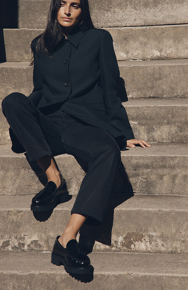 Person wearing a black outfit sitting on stone steps.