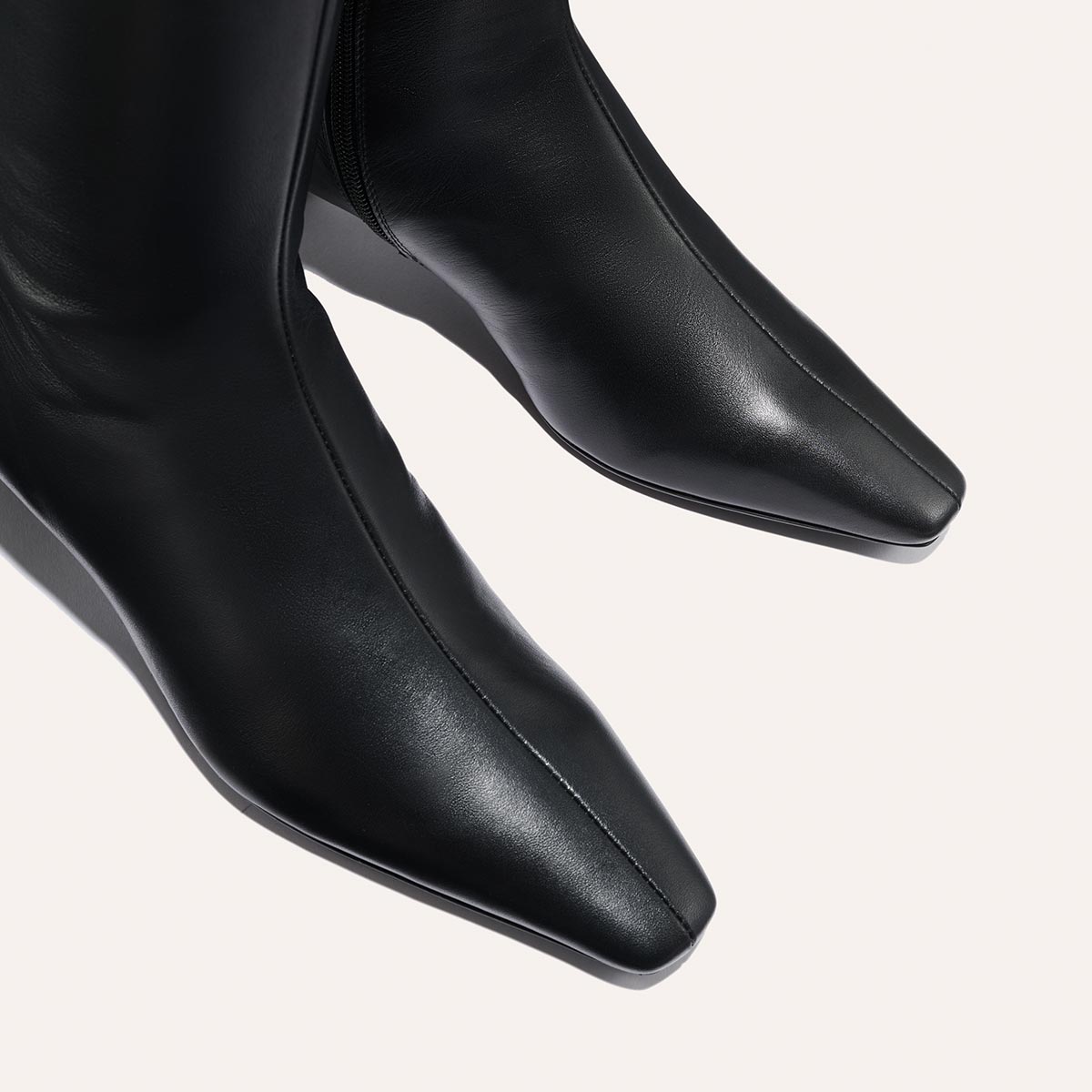 Close-up of The Imogen - Black Calf boots by Margaux, featuring a square toe, smooth polished leather, and modern design, displayed on a light background.