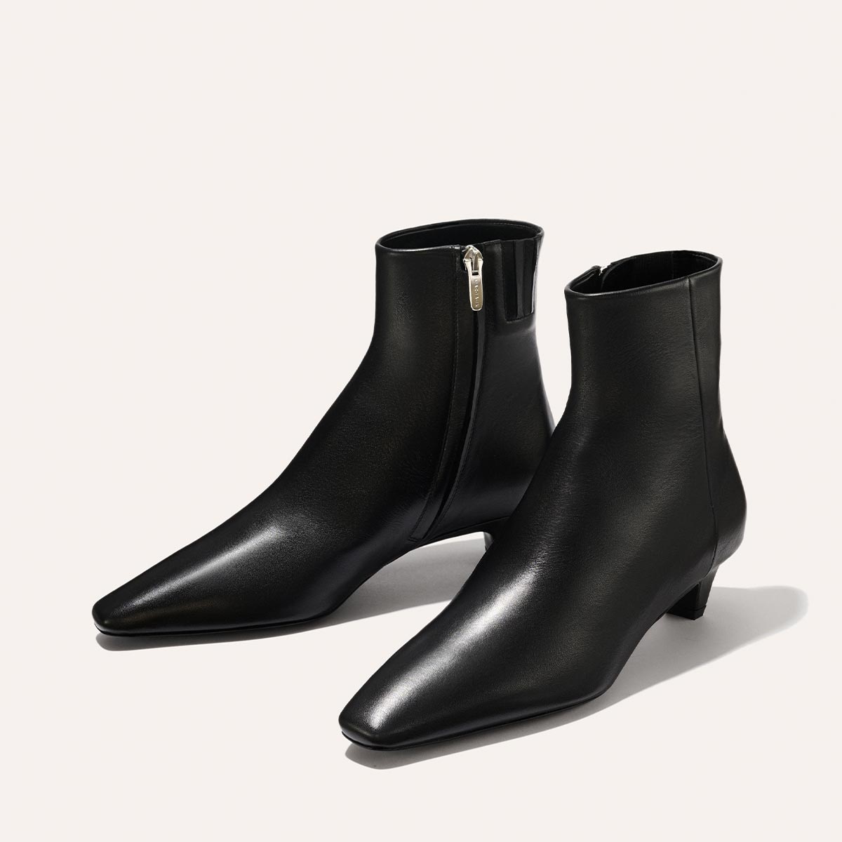 The Alex Mill x Margaux: The Inga - Black Calf by margaux-development features black leather, a kitten heel, side zippers, and pointed toes—a chic ankle boot perfect for stylish walks in New York City.