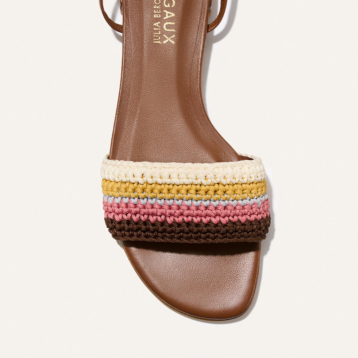 The Isla Wrap Sandal by Margaux features a cognac brown square toe and a wide strap with multicolor crochet stripes in cream, yellow, pink, blue, and dark brown.