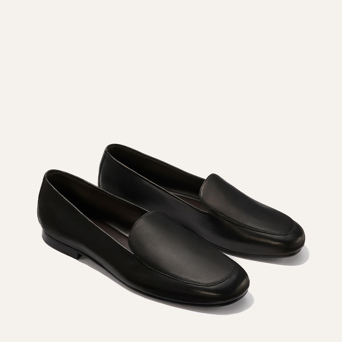 The James Loafer - Black Nappa by Margaux is a pair of sleek black leather loafers, showcased against a plain, light background.