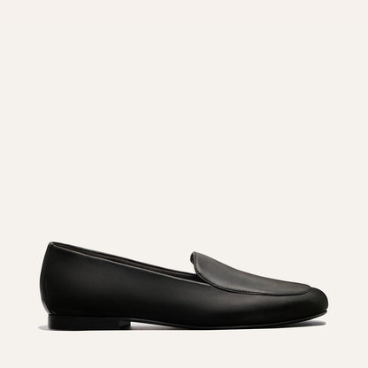 The James Loafer - Black Nappa by Margaux features a sleek black leather design with a low heel and minimalist style, shown in profile against a plain light background.