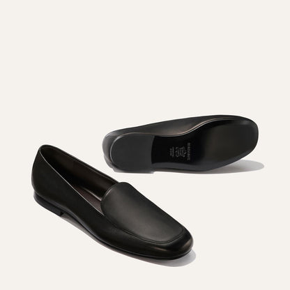 The James Loafer - Black Nappa by Margaux: one black leather loafer stands upright while the other lies on its side to show the sole, both set against a plain light background.