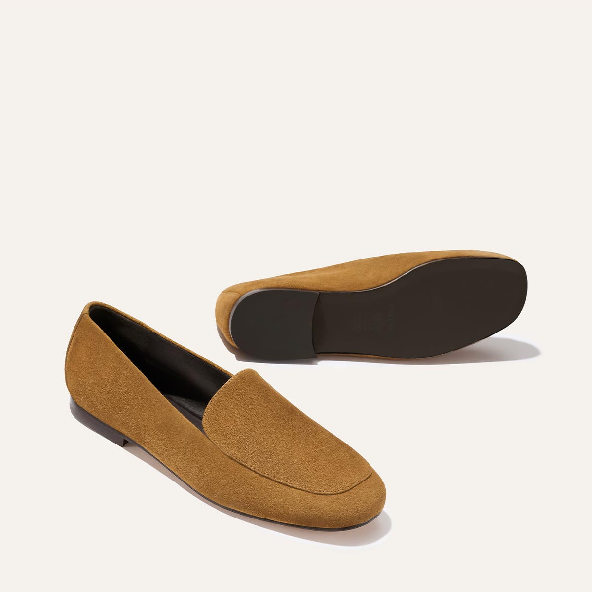 The James Loafer - Cedar Suede by Margaux: a pair of light brown suede loafers with dark brown flat soles, displayed upright and on its side to highlight the sole.