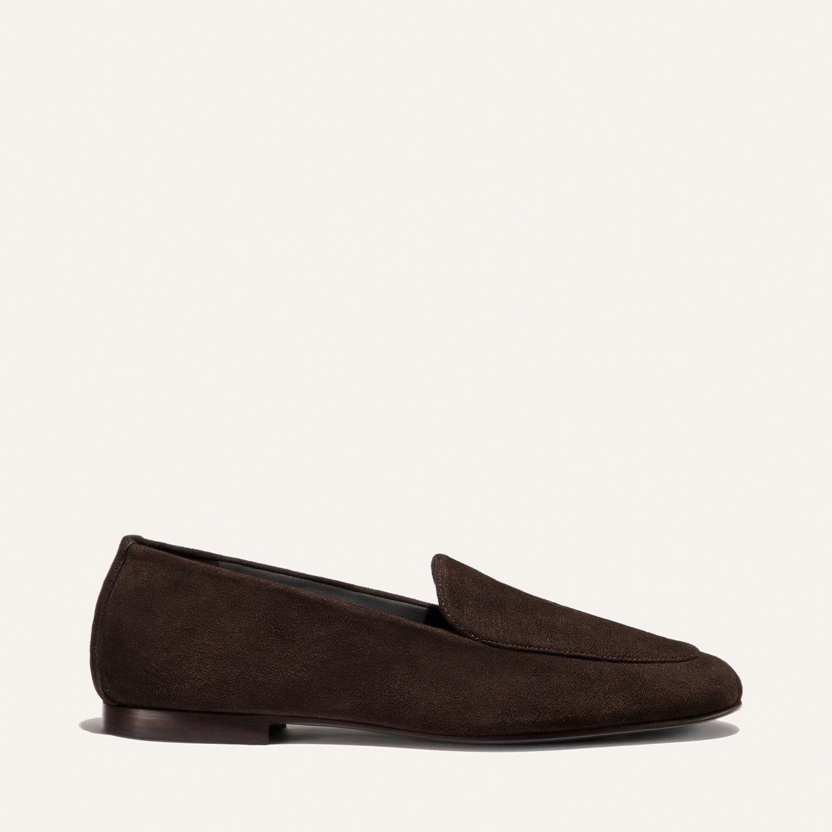 The James Loafer - Molasses Suede by Margaux is displayed in profile against a plain light background, featuring rich dark brown suede, a low heel, elegant sacchetto construction, and a tailored fit.