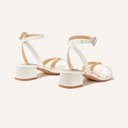 The Lena Sandal in metallic Ivory Satin, featuring perfectly placed straps, a crystal buckle, and a comfortable 1.5-inch block heel.