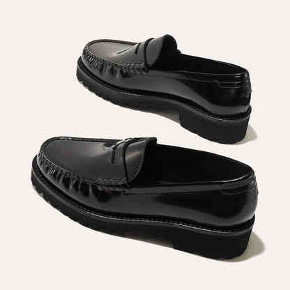 The Louisa Loafer in Black Calf, a leather penny loafer with chunky lug sole, featuring high-shine abrasivato leather and a lightweight design.