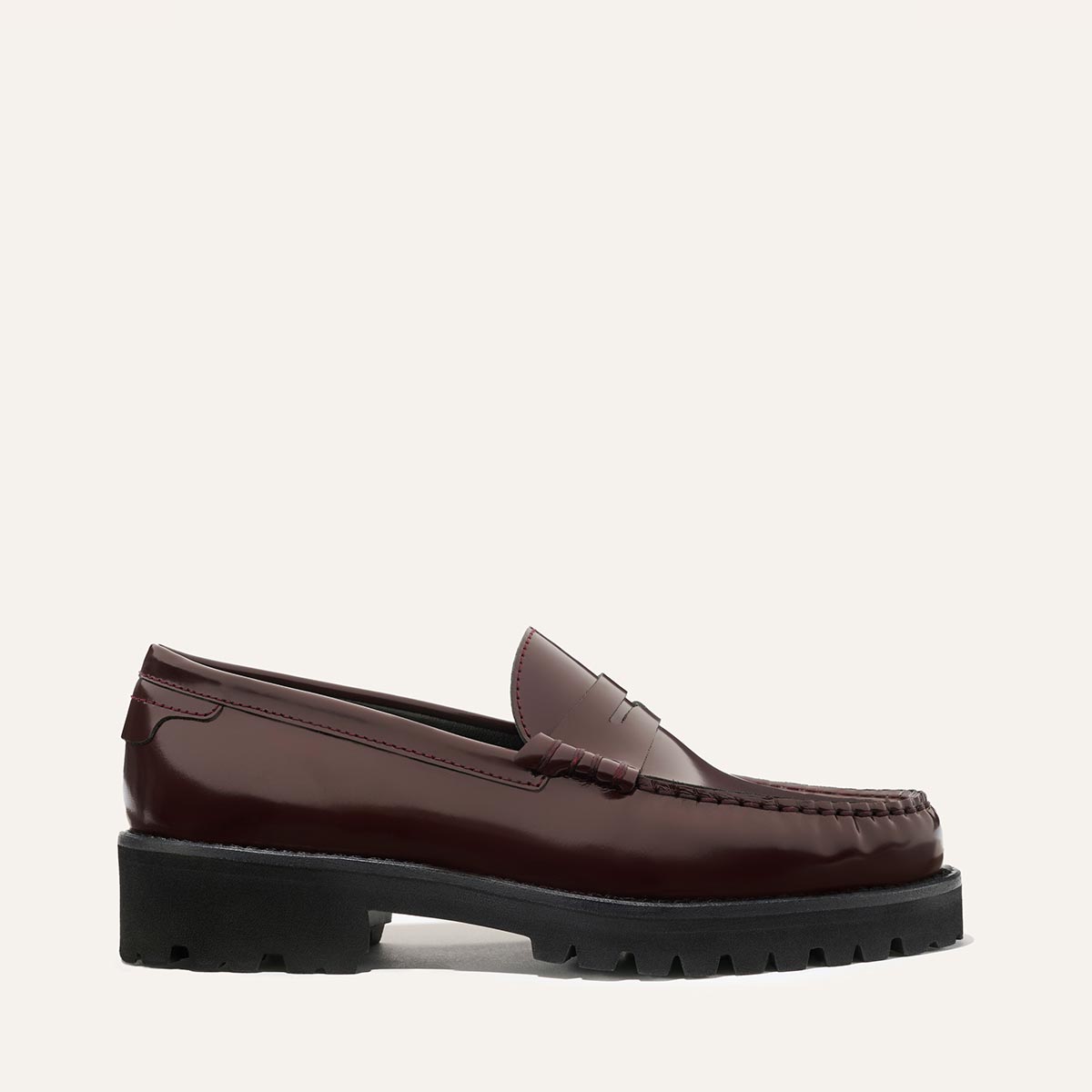 The Margaux Louisa Loafer in burgundy calf leather, featuring a penny slot detail and chunky black lug sole, is displayed in side profile against an off-white background.