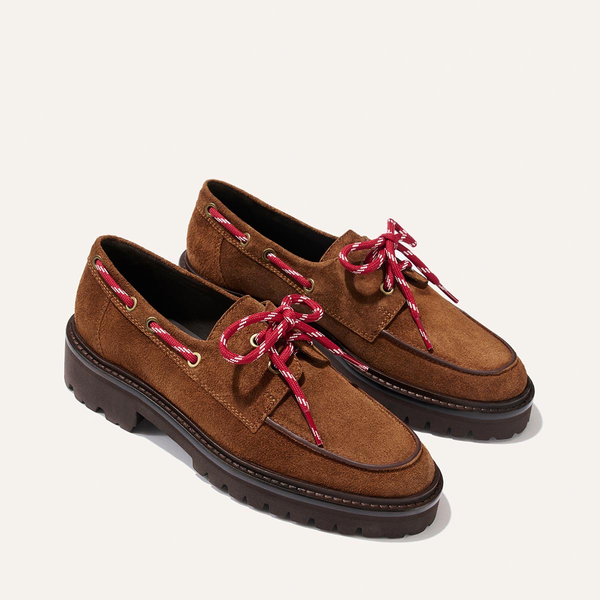 A pair of Margaux’s The Marine Loafer in Saddle Suede, featuring chunky dark soles and red-and-white striped laces, displayed on a plain off-white background.
