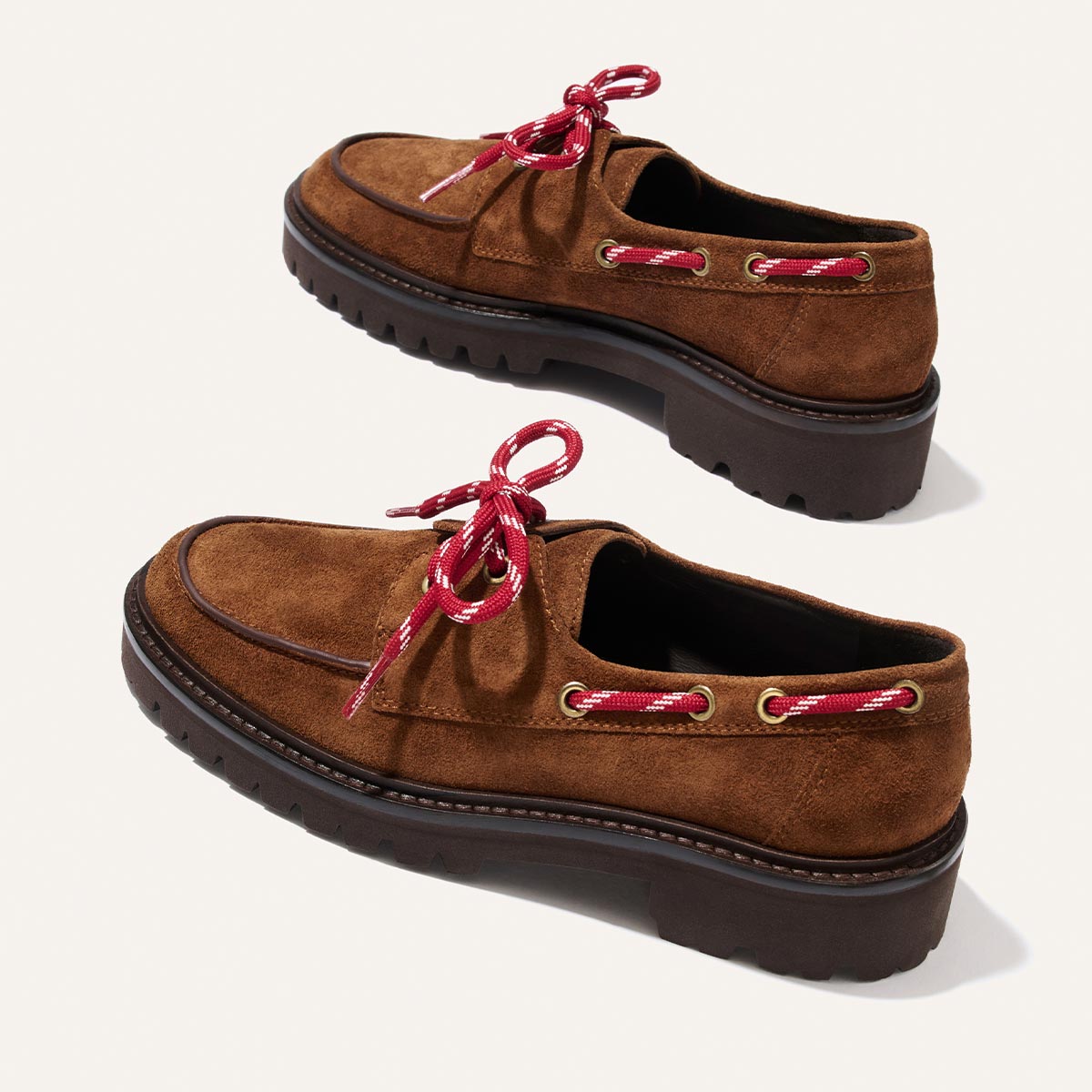 The Marine Loafer - Saddle Suede by Margaux, featuring brown suede uppers, dark chunky rubber soles, and red-and-white striped laces, displayed on a light background.