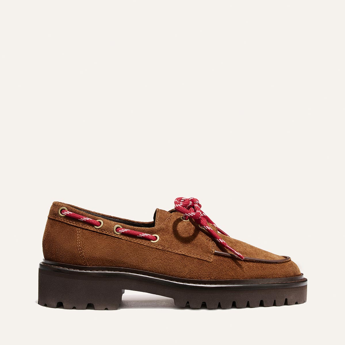 The Marine Loafer - Saddle Suede by Margaux is a brown suede shoe featuring a chunky black sole, red laces, and metallic eyelets. Designed with a casual, rugged aesthetic, it highlights visible stitching and a textured outsole for enhanced grip.