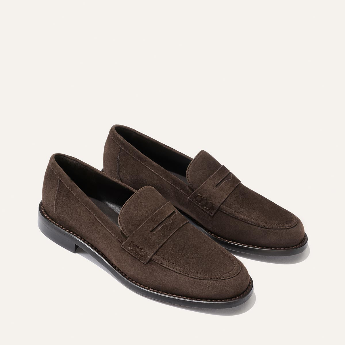 A pair of Margaux’s The Marlowe Loafer in Umber Suede, featuring black soles, displayed on a plain light background.