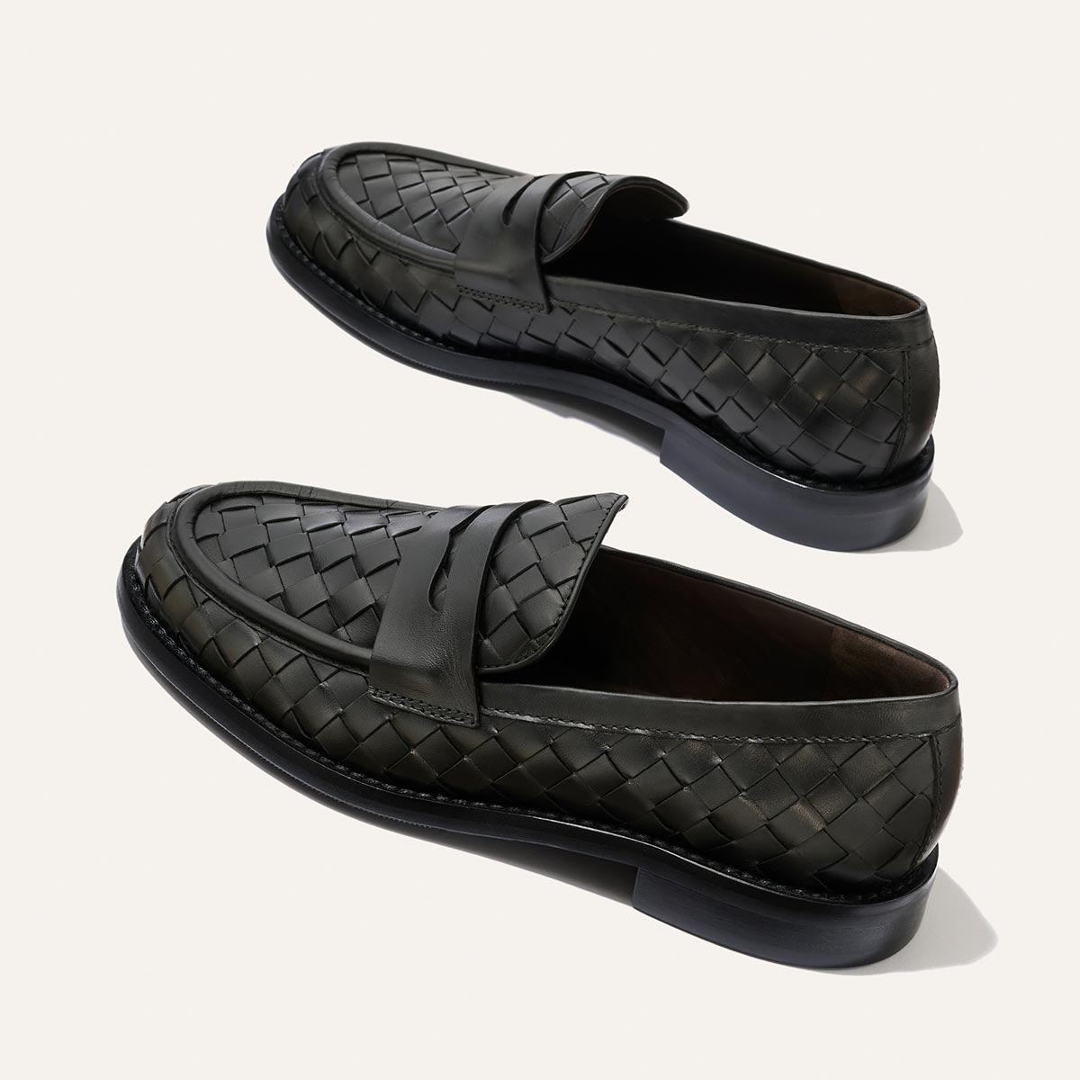 A pair of Margaux’s The Marlowe Loafer in Black Woven Pasado Calf are displayed on a light background, showing both side and top views—a timeless piece for any refined wardrobe.