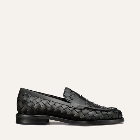 The Marlowe Loafer by Margaux in Black Woven Pasado Calf features a low heel and rounded toe, shown in profile on a simple light background—a modern loafer designed to be a closet staple.