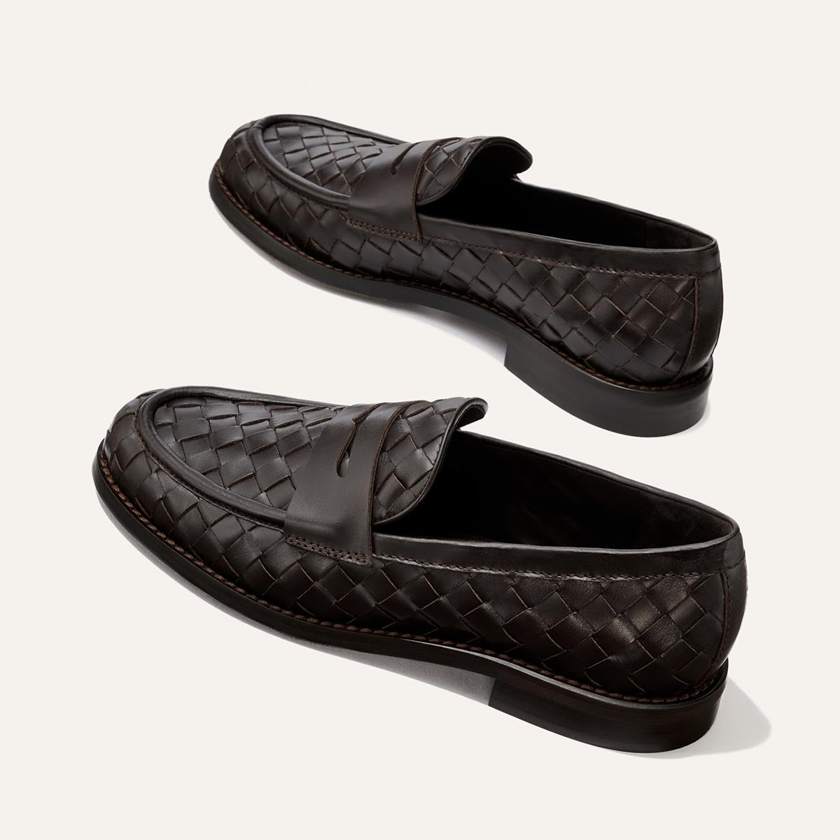 A pair of Margaux’s The Marlowe Loafer in Brown Woven Pasado Calf, featuring modern woven leather and black soles, displayed on a light background.