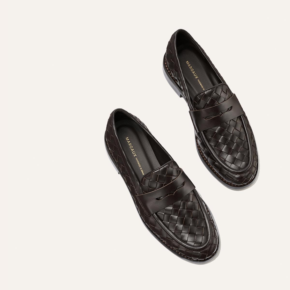 Introducing The Marlowe Loafer in Brown Woven Pasado Calf from Margaux, featuring an elegant woven leather design and classic penny slot details—these modern loafers are a timeless wardrobe essential, beautifully presented from an overhead view on a light background.