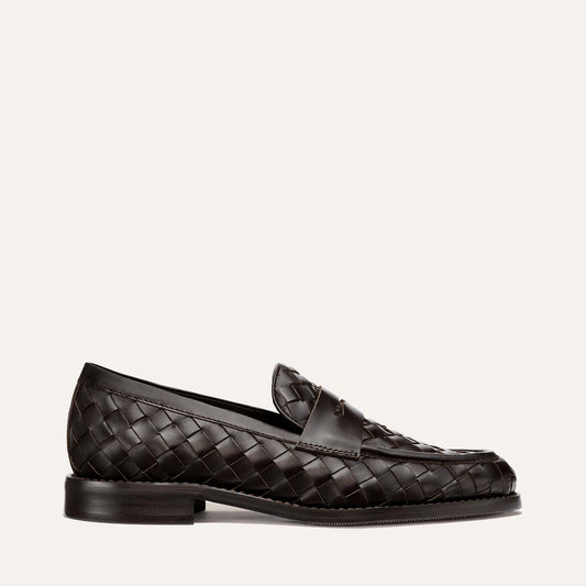 The Marlowe Loafer by Margaux in Brown Woven Pasado Calf features a dark brown woven leather design, a low heel, and a smooth sole. Shown in profile against an off-white background, it’s an effortlessly modern staple for any wardrobe.