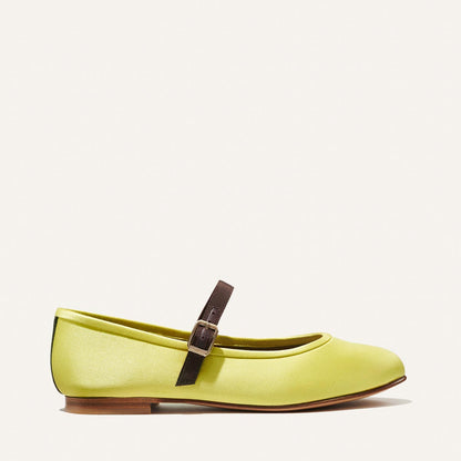 The Demi Jane - Citron Satin by Margaux: a light green flat with rounded toe, brown strap, and small buckle. Shown in side profile on a white background, it exudes elegant femininity.