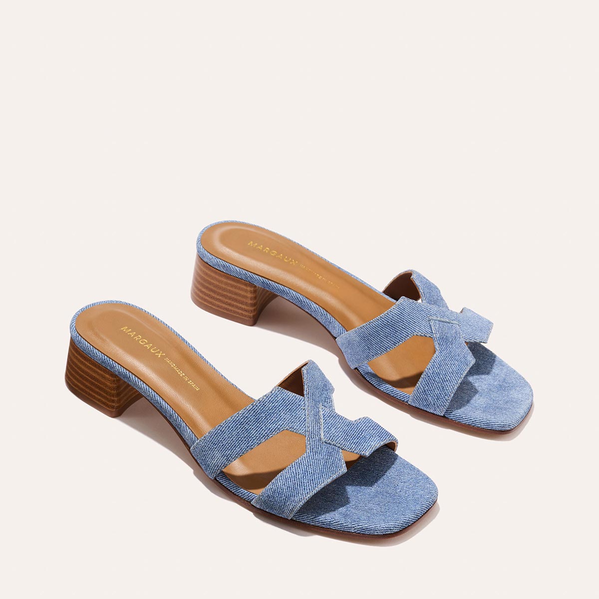 The MX 35 - Denim Suede by Margaux-development: walkable women’s open-toe heeled sandals with light blue crisscross denim straps and brown stacked block heels, shown on a light background.