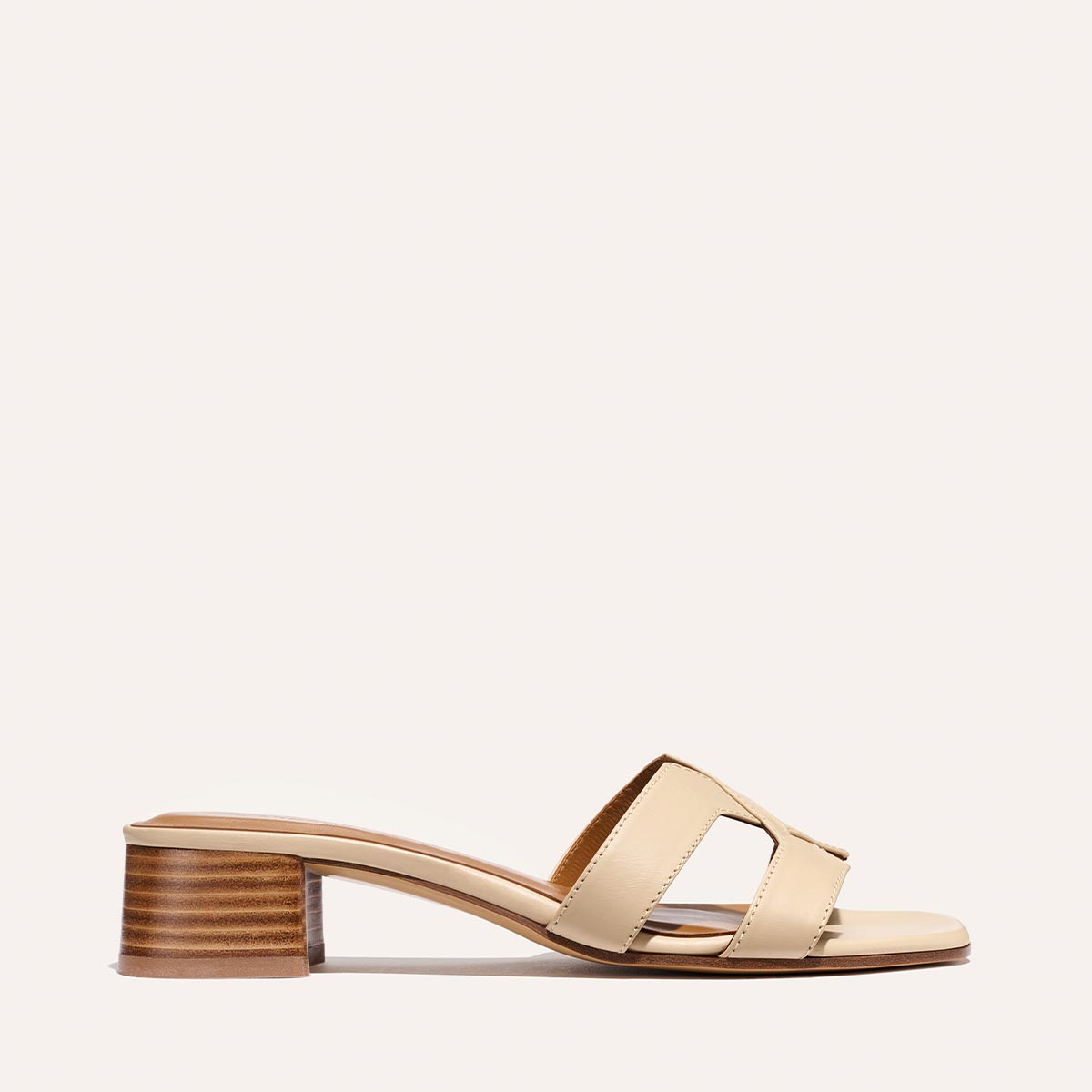 The Margaux MX 35 - Latte Calf sandal showcases a beige block heel, open toe, wide cutout straps, and a low stacked wooden heel, photographed against a plain light background.
