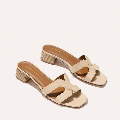 The Margaux MX 35 - Latte Calf features beige heeled sandals with open toes, crisscross straps, and a comfortable block heel, styled on a light background for effortless walkability.
