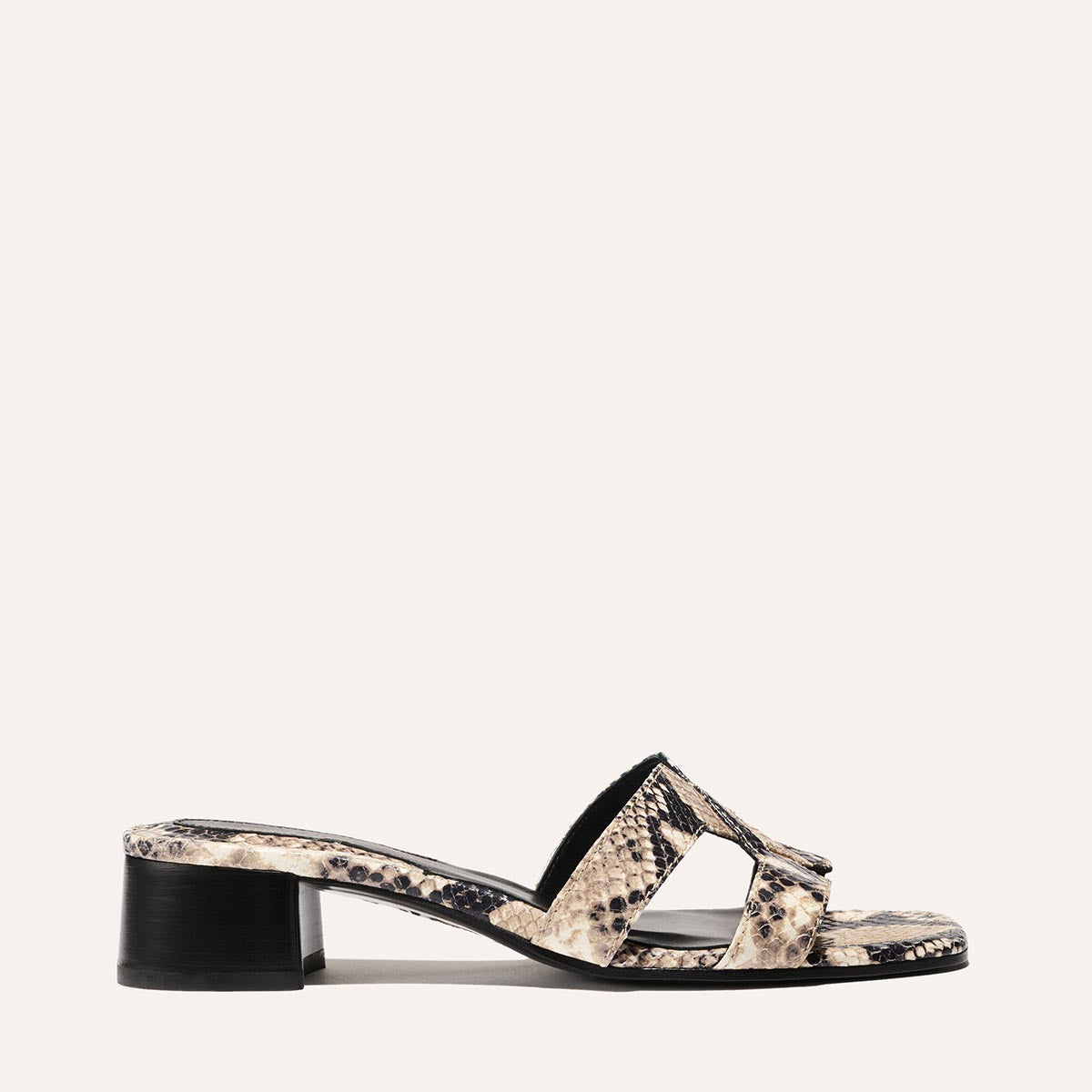 The MX 35 - Natural Python Embossed by margaux-development is a single sandal with a low block heel, beige and black python-embossed pattern, and wide crisscross straps, set against a plain light background for chic style and comfort.