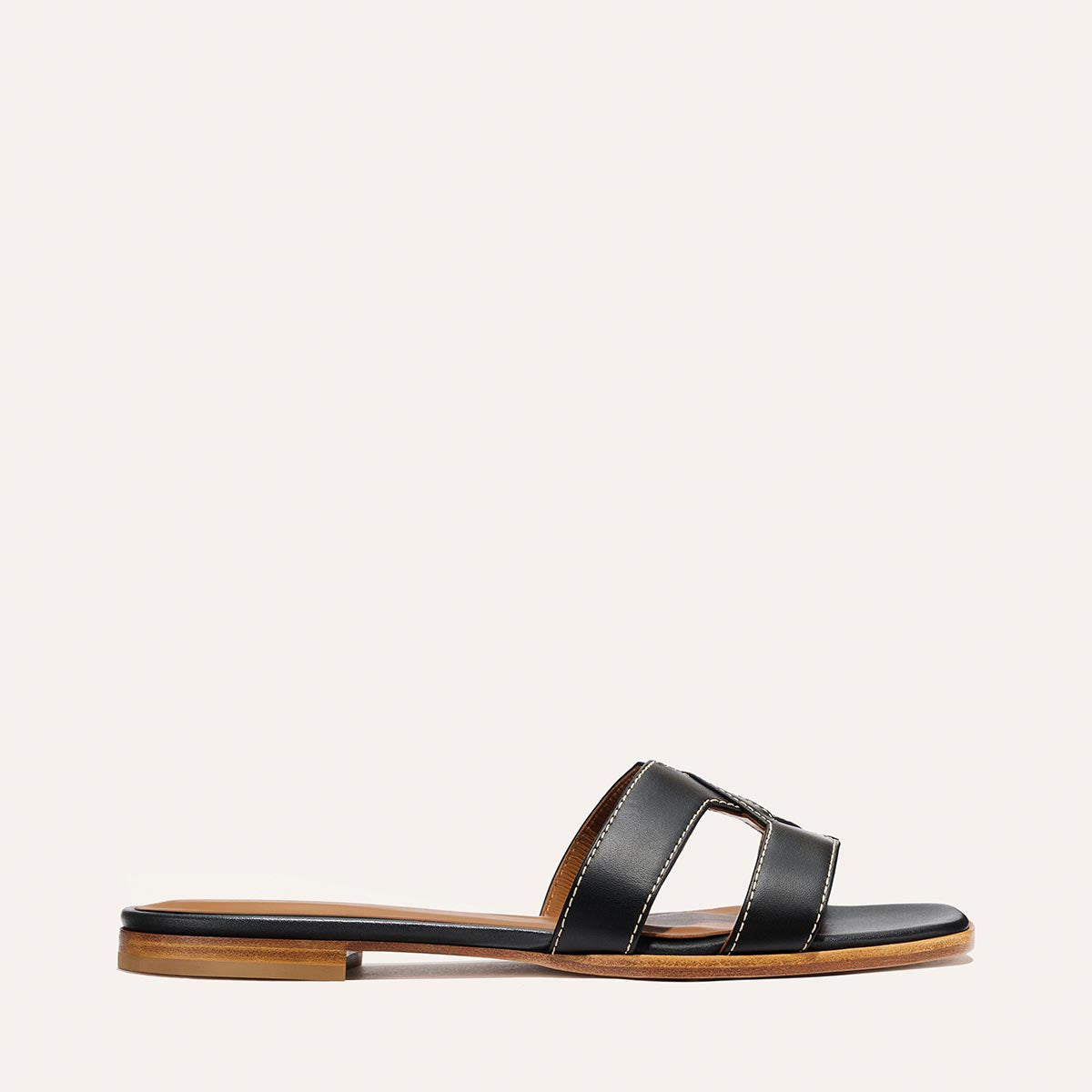 The MX Sandal - Black Calf by Margaux features a black leather H-shaped double strap, an open toe, and a brown sole, displayed on a plain light background.