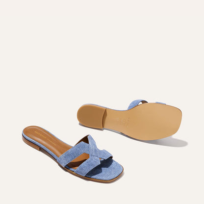 The MX Sandal - Denim Suede by Margaux features light blue crisscross straps and tan soles, displayed from the top and bottom on a plain, off-white background.
