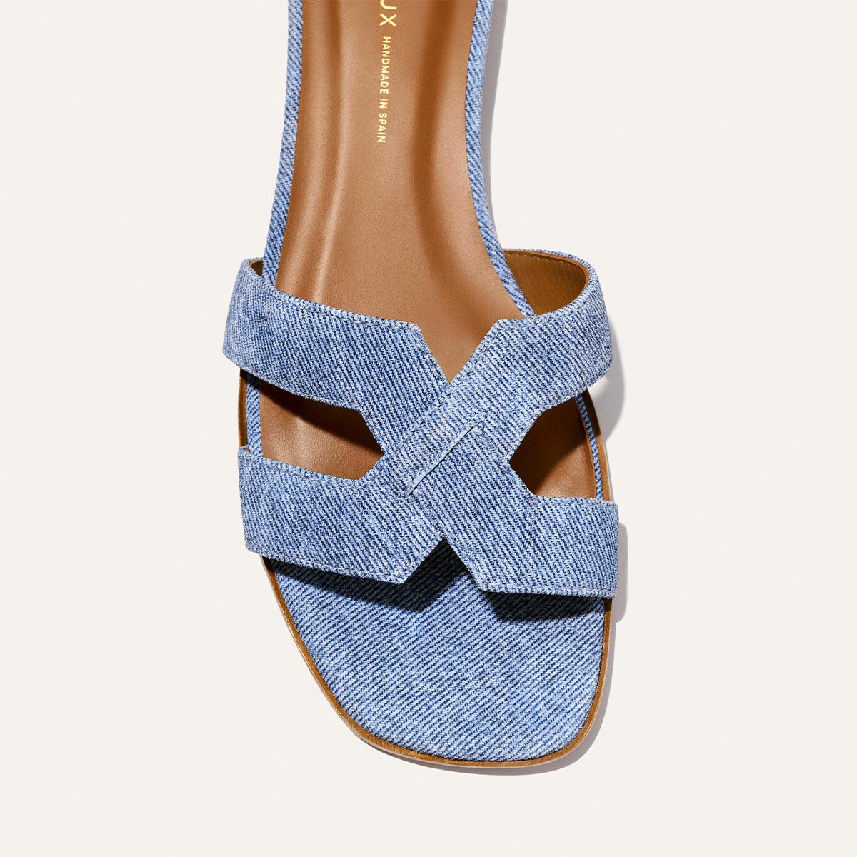 The MX Sandal - Denim Suede by Margaux is shown from above, displaying its light blue denim crisscross upper, brown insole, and square toe against a light background.