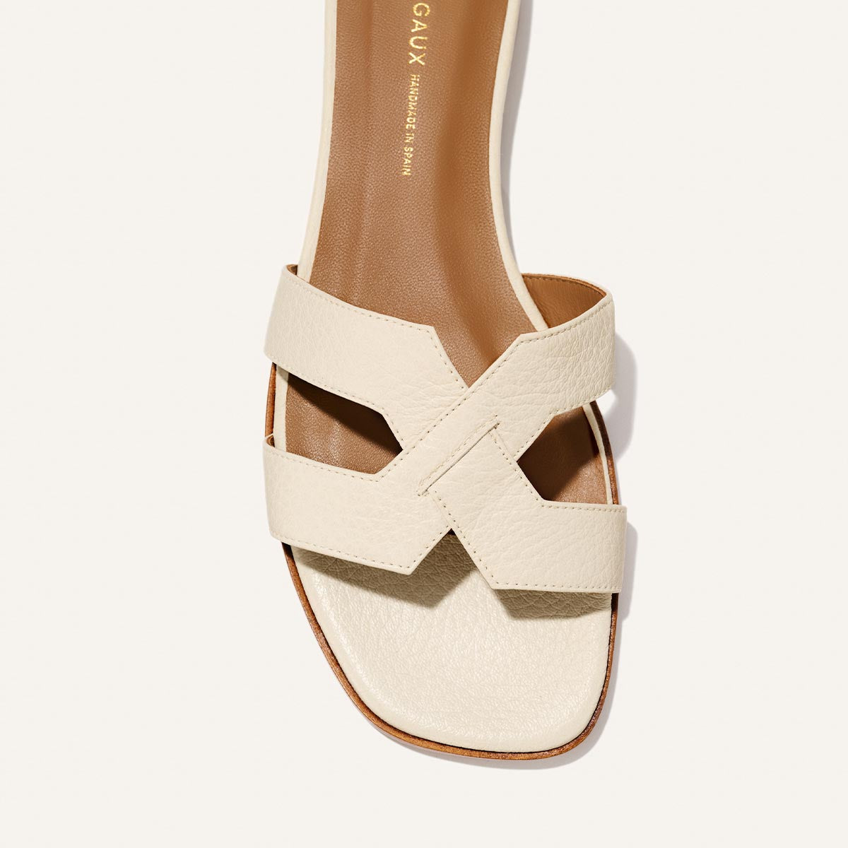 A close-up of Margaux's The MX Sandal in Ecru Tumbled Nappa, featuring premium leather, a square toe, two wide overlapping straps with geometric cutouts, a tan insole, and minimal stitching—ideal for effortless everyday style.