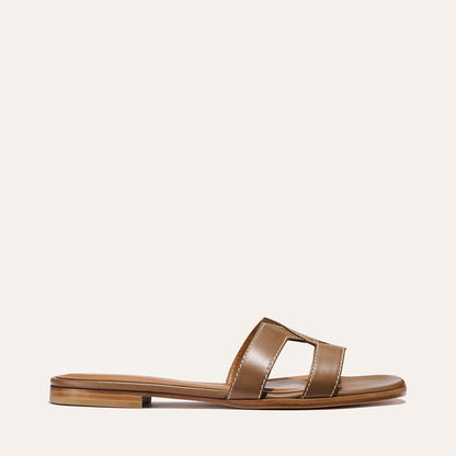 The MX Sandal - Mocha Calf by Margaux is a brown leather flat with a low heel, open toe, and cut-out strap, shown on a neutral background.