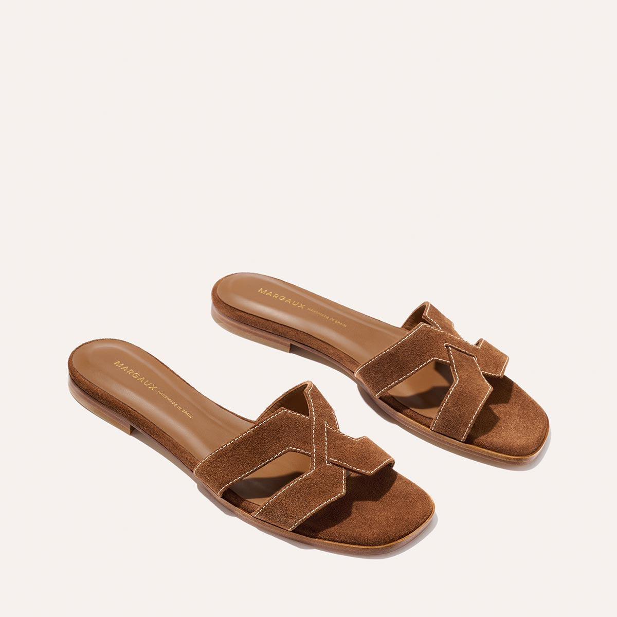 The MX Sandal - Saddle Suede by Margaux features brown suede, open toes, and crisscross straps—crafted from luxe leather for everyday wear—shown on a light background.