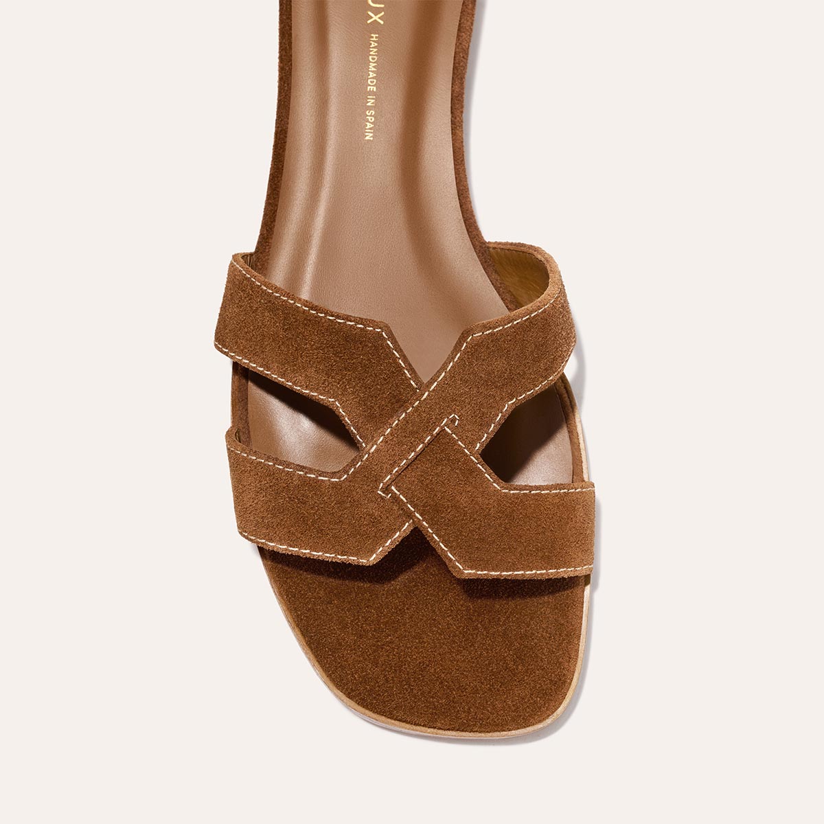 A close-up of Margaux’s The MX Sandal in Saddle Suede, featuring geometric cutouts, white stitching, an open toe, and a squared front—ideal for effortless everyday style.