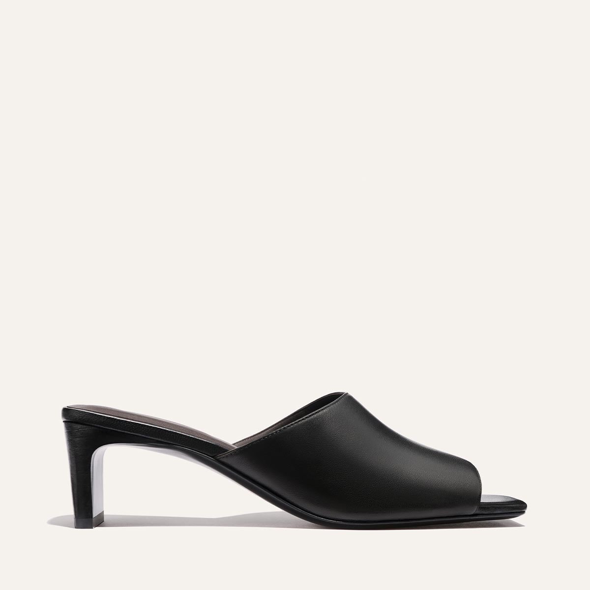 The Naomi 50 - Black Nappa by Margaux: a black open-toe mule with a soft leather upper, mid-height square block heel, and sleek minimalist design, shown on a plain white background.