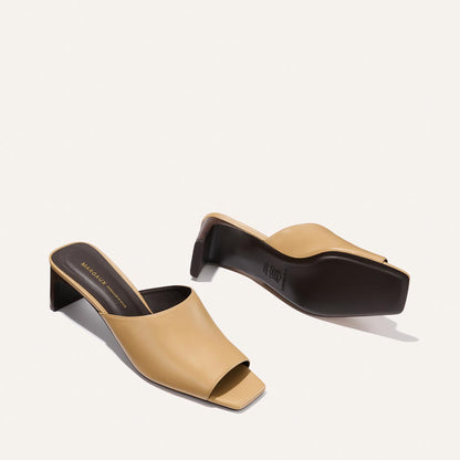 Pair of beige high-heeled mules on a light background