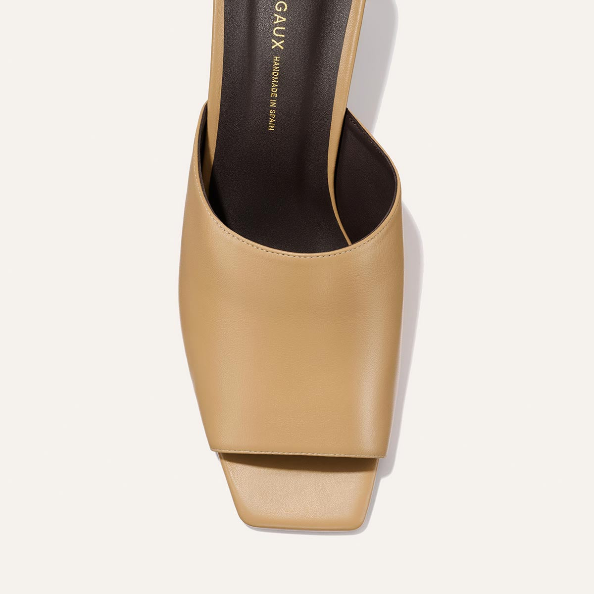 Beige high-heeled shoe with 'GAUX' branding on a light background