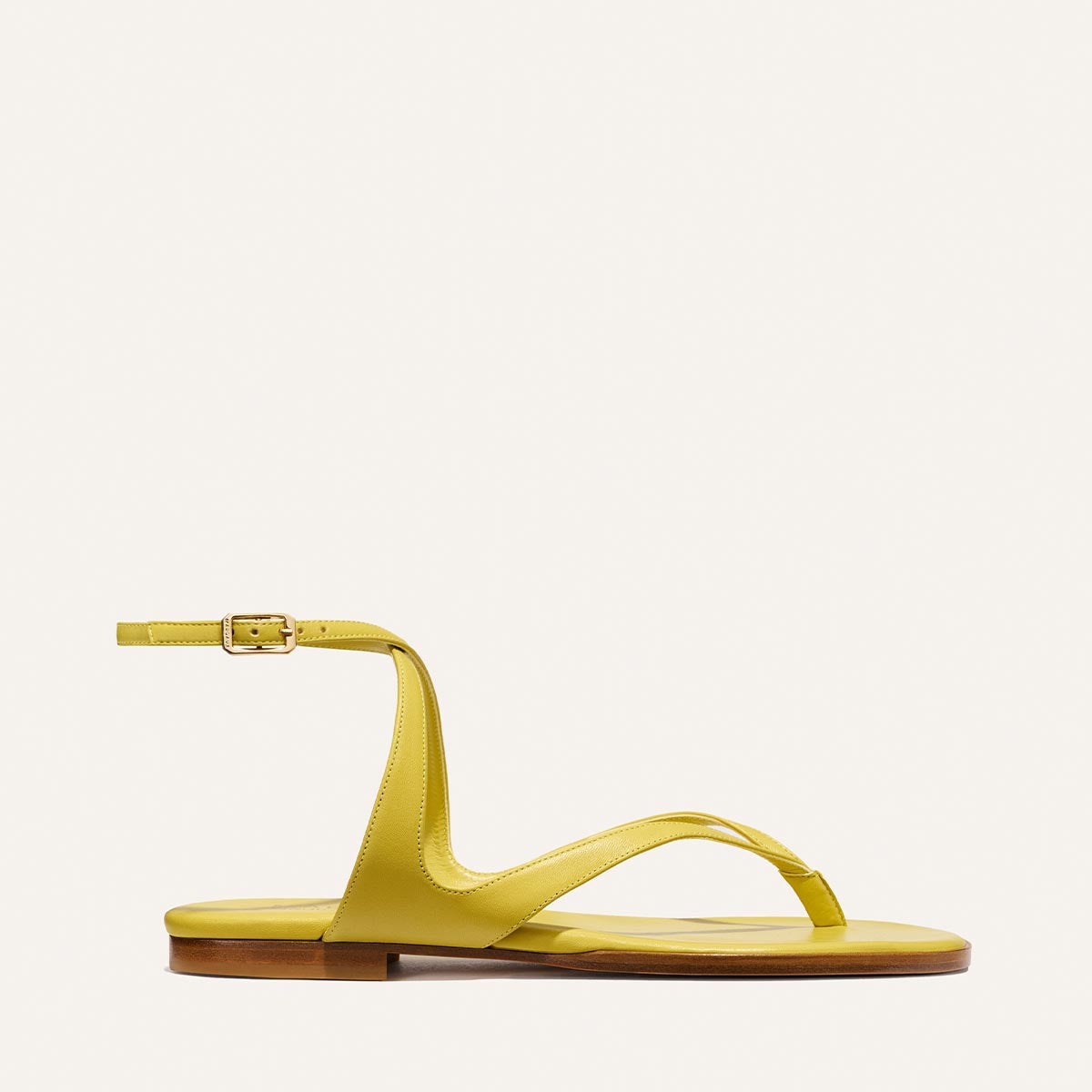 The Palermo Sandal - Chartreuse Nappa by Margaux features a minimalist yellow flat design with a thin ankle strap, buckle, and toe loop, radiating playful charm and style on a plain light background.