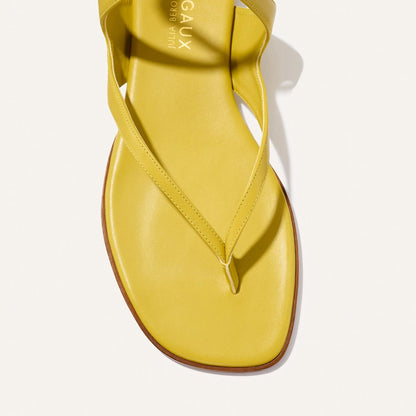 A close-up of The Palermo Sandal - Chartreuse Nappa by Margaux, featuring a yellow square toe and thong strap, is photographed from above on a white background, highlighting its playful elegance inspired by Julia Berolzheimer.