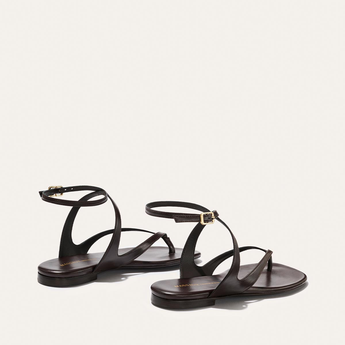 Pair of brown sandals with thin straps on a light gray background